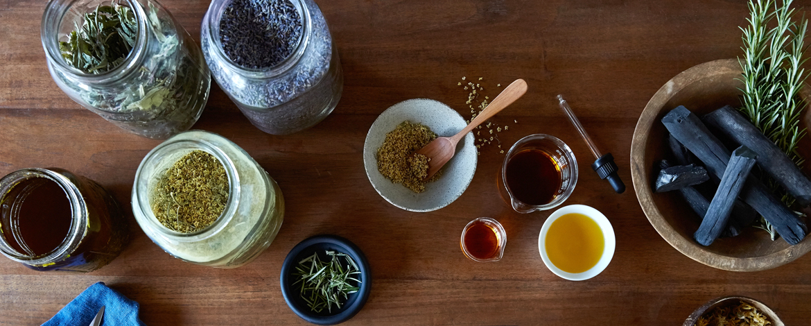 Spices and herbs in jars and bowls on a wooden table.