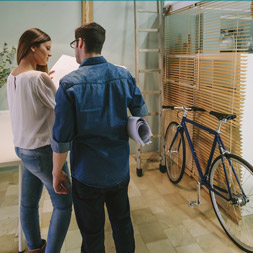 A man and a woman looking at building plans with a bike in the background.