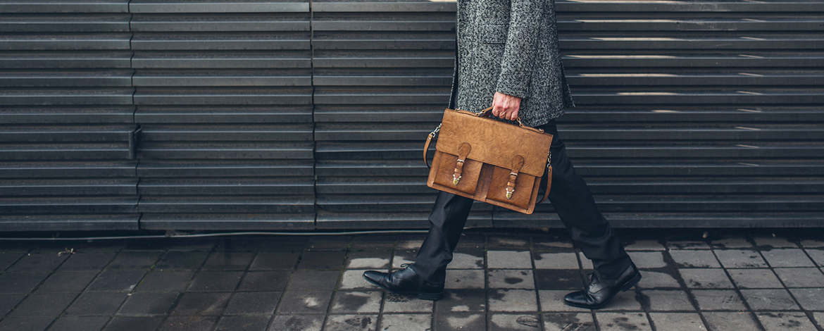 Male professional walking carrying a tan briefcase