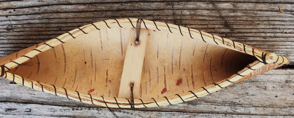 Aerial view of the inside of a canoe sitting on a weathered dock.